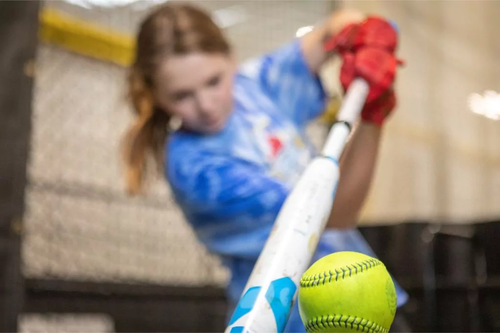 blurred image of female batter hitting softball